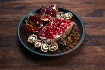 Sandwich with soft cheese and pomegranate seeds, next to walnuts and raisins