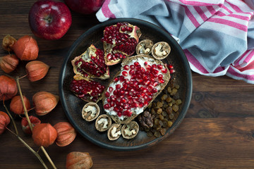 Quick and healthy breakfast. Sandwich with soft cheese and pomegranate seeds, nuts and raisins on a brown wooden board