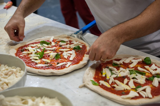 Preparing Pizza Margherita on a marble top. Pizzaiolo puts pizza dough on the peel. Selective focus   
