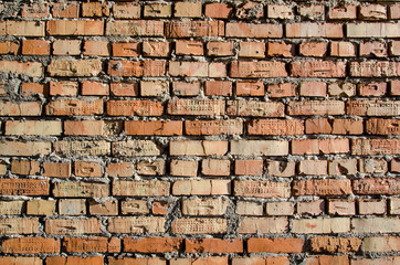 Old brick wall, old texture of red and orange blocks of stone. Closeup