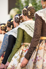 Falleras seen from behind. Dresses with floral designs and typical hairstyle of the fallas with...
