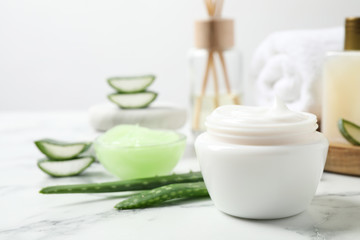 Obraz na płótnie Canvas Open jar of cream and aloe on white marble table. Organic cosmetics