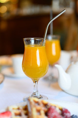 morning Breakfast or brunch in the restaurant. table with drinks and food. a glass of fresh orange juice and a metal drinking straw. selective focus