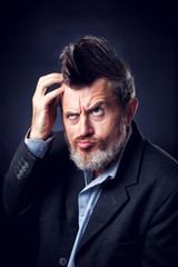 Fototapeta premium A portrait of bearded man with iroquois wearing suit thinkig about something. People and emotions concept