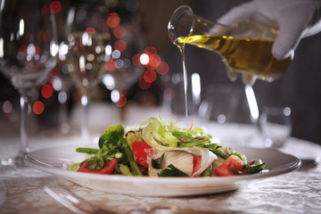 Olive oil is poured on the prepared salad. Arm out of focus. Photos without a face.