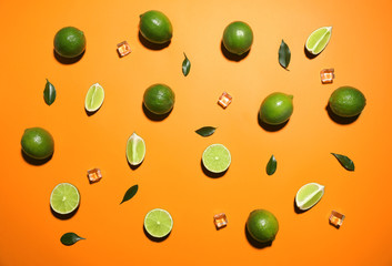 Flat lay composition with fresh juicy limes and ice cubes on orange background