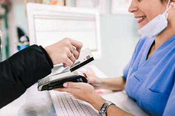 Young woman paying in a veterinary with credit card