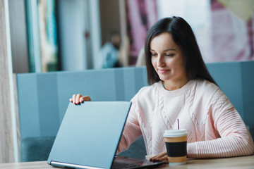 Girl in a cafe opens a laptop.