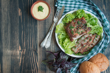 Baked pork belly with spices. Sliced breast served with greens. Traditional dish of Ukraine. Close-up. Space for text.