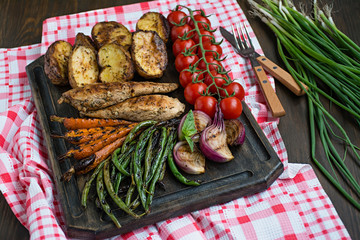 Grilled vegetables on a cutting board on a dark wooden background. Dark wooden background.