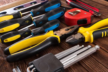 Work tool of the wizard. Screwdrivers, pliers, wire cutters, building level, tape measure, hammer, wrenches, square and other tools on a wooden surface. Free space for text.