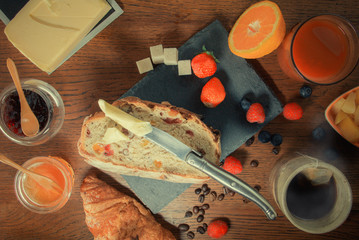 Petit déjeuner varié avec pain aux fruits secs et céréales jus d'orange frais miel salade de fruits fruits rouges beurre à tartiner et une tasse de thé et croissant au beurre