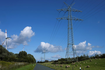 Windräder und Strommasten und Schafherde in Niedersachsen an der Nordseeküste - Stockfoto
