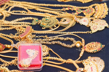 Selected Focus on Golden Jewellery or Jewelry Necklace Garland With Pendants or Lockets on Blue Background