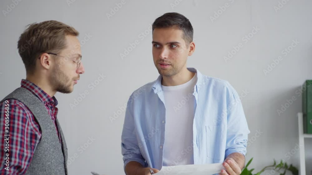Wall mural tilt up medium shot of two young creative web designers discussing ideas and application interface s