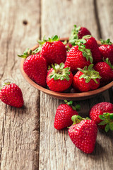 Freshly picked Strawberry in wooden bowl on wooden background. Healthy eating and nutrition.