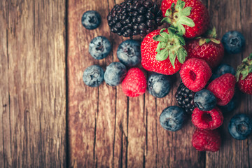 Fresh Summer Berries mix with Strawberry, Raspberry, Red currant, Blueberry and Blackberry on wood background.