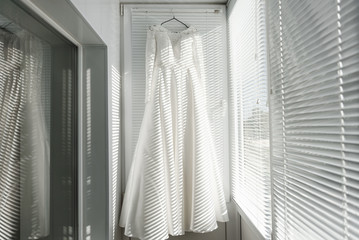 White wedding dress on the clothes hanger. Wedding dress on the balcony. Fashion look