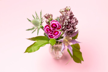 bouquet of flowers on pink background, top view