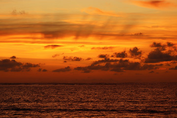 Fototapeta na wymiar Sunset on a beach, evening sea background. Dark water and dramatic orange sky with clouds on the horizon, concept of romantic travel
