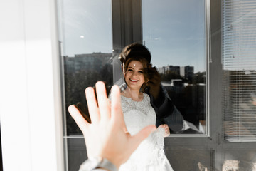 Portrait of young gorgeous bride on the balcony. Wedding day gatherings. Beautiful girl dresses and gathers for a wedding ceremony in apartaments while waiting for the groom. Bride's morning