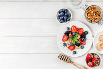 Healthy breakfast with granola, fruits, berries on white background.