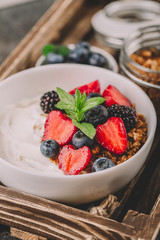 Healthy breakfast with granola, yogurt, fruits, berries on dark metal background. Summer homemade breakfast.