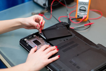 female hands with red manicure repair a laptop