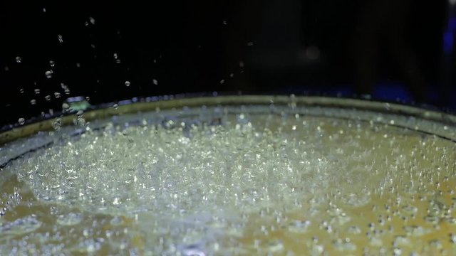 Drops water jumping on the drum on black background. Close up of drums perfused with water for special effect. Shot from slight low angle looking up