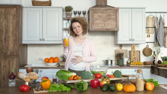 Young Pregnant Woman With Glass Of Orange Juice In The Kitchen