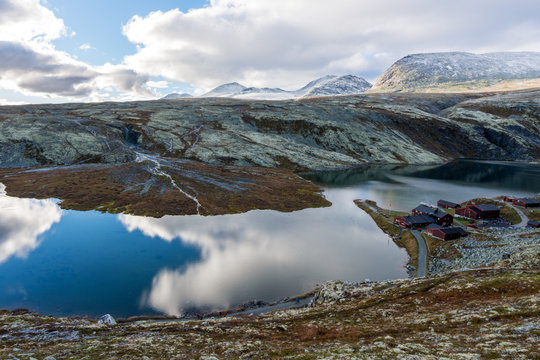 Panorama image of Rondvassbu tourist center in the middle of Rondane national park in Sel, Norway. Rondvatnet lake and ula river in the foreground. Snow covered mountains in the background. 