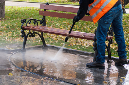 Cleaning The Park With Water In Autumn. A Worker Cleans The Park