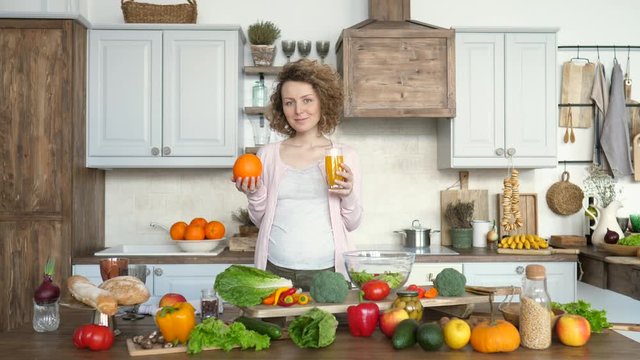 Pregnancy And Healthy Diet Concept. Pregnant Woman With Orange Juice On Kitchen.