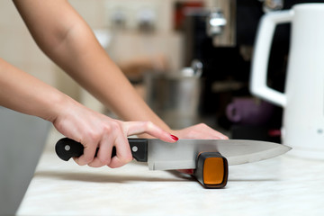 A lonely woman does men's work, sharpening a knife