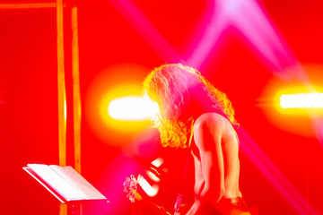 Guitarist without a shirt during the concert, in stage lights.