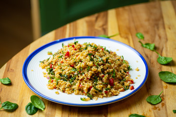 Homemade vegan food (vegan salad) from bulgur cereal with fresh vegetables, spinach, avocado, spices and olive oil. Healthy bio eco food concept