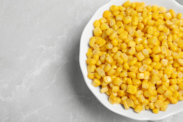 Delicious canned corn in bowl on marble table, top view. Space for text