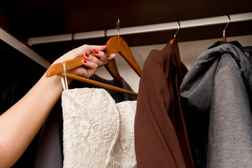 the bride takes out a dress from the closet with casual clothes