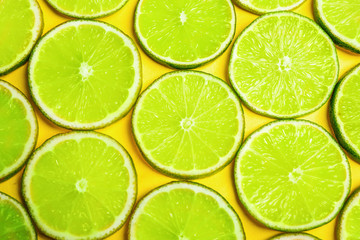 Fototapeta na wymiar Juicy fresh lime slices on yellow background, flat lay