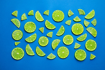 Juicy fresh lime slices on blue background, flat lay