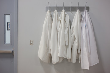 Lab coats hanging on wall at pharmaceutical laboratory
