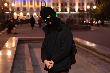 Fototapeta premium man in a balaclava in the middle of the night city. 