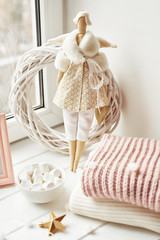 Handmade doll and marshmallows near window. Cozy winter morning. Christmas concept and mood. Postcard Template
