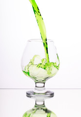 Green alcohol cocktail in glass with splash on white background, selective focus on the liquid jet