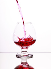 Pink alcohol cocktail in glass with splash on white background, selective focus on the liquid jet
