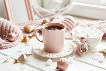 Christmas decor, balls, woolen plaid on the window background, home comfort concept, seasonal winter celebrations. Postcard Template. Christmas pink cup with marshmallow.