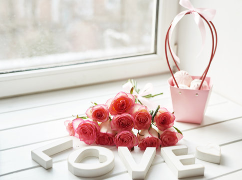Valentine Card. Composition with fresh roses and photo frame on window sill. Space for text. Floral composition with inscription Love. Mother's day and March 8 card