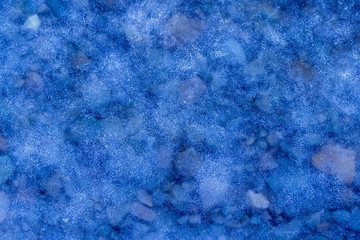 blue texture of an thin ice surface with pure transparent water ,cold clear snow cryslallized background ,winter frozen lake side close up , abstract macro wallpaper
