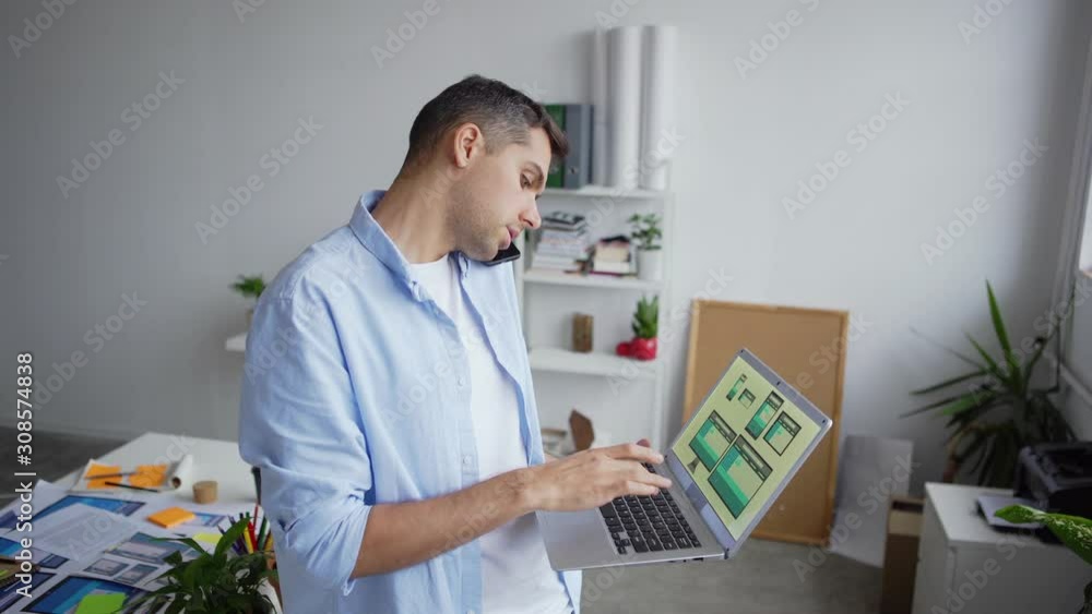 Wall mural tilt up zoom out of printed application interface samples on office desk and young entrepreneur stan