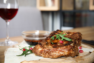 Delicious grilled ribs on wooden board indoors, closeup
